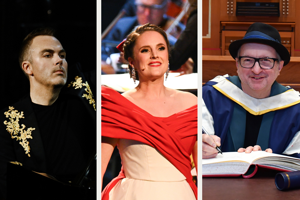 A man wearing a black and gold top, a woman in a red and cream ballgown, a man wearing a gown, hat and glasses signing a book